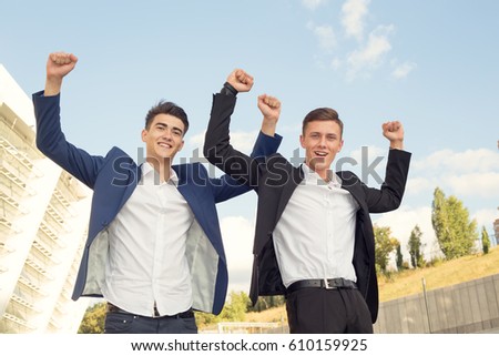 Concept - business champion. Two young men raised his arms up as a sign of victory and success in business. Teamwork.