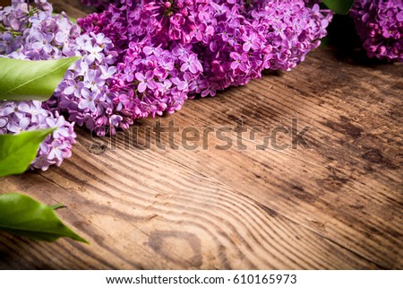 Bunch of lilac flowers on dark brown wood table with empty space for text, selective focus