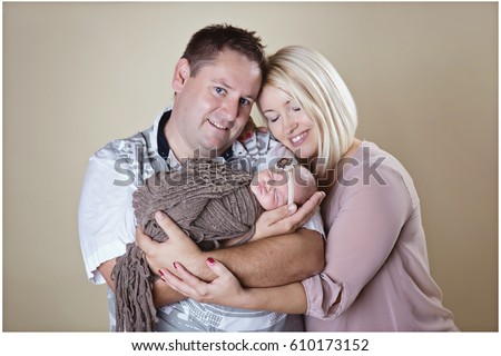 We can see a happy family during their professional photo-shoot. Baby is sleeping peacefully in her father's hands.