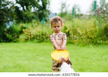 Boy with funny face expression and tongue playing with dog