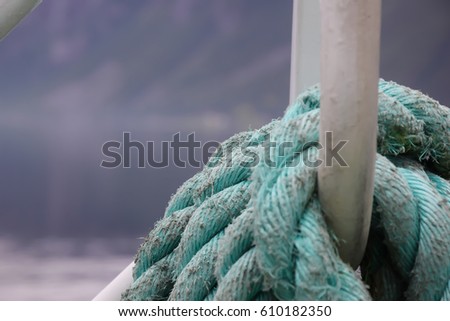 Mooring rope wrapped around the cleat on ship with norwegian fjord background