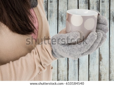 Digital composite of Close up of woman holding polka dot mug against wood panel