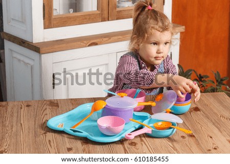 little girl playing toy baby dishes at home
