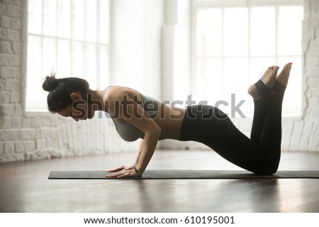 Young attractive woman doing Warming up, practicing Exercises for chest, arms, and shoulders, knee Push ups or press ups, working out, wearing sportswear, full length, white loft studio background  Royalty-Free Stock Photo #610195001