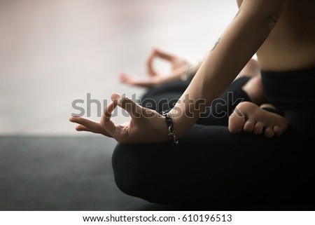 Young yogi woman practicing yoga concept, sitting in Padmasana exercise in studio or at home, Lotus pose with mudra gesture, working out on black mat, wearing sportswear pants, close up of hands  Royalty-Free Stock Photo #610196513