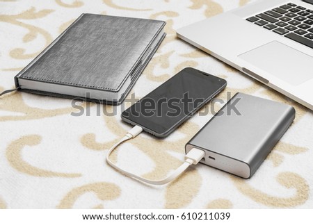 Business computer, notebook and cell phone charge from power bank on sofa