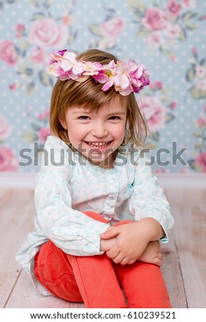 The little girl with a wreath of flowers on her head looking into the camera and smiling