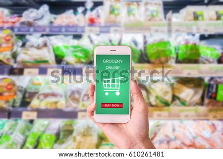 Woman holding mobile with grocery online on screen with blur supermarket background