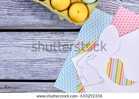 Easter eggs and patterned paper. Colorful paper on gray wood. Make Easter decorations at home.