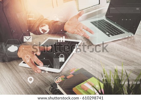 businessman working with laptop computer and digital tablet and book and document on wooden desk in modern office with virtual icons interface
