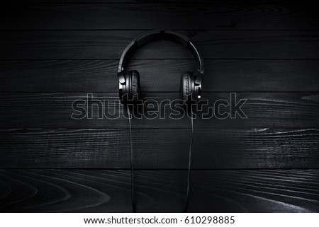 Black headphones on brown wooden dark background