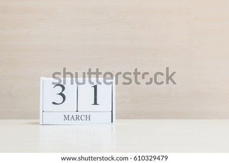 Closeup surface white wooden calendar with black 31 march word on blurred brown wood desk and wood wall textured background with copy space , selective focus at the calendar