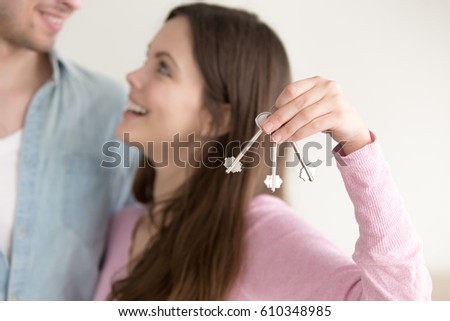Couple successfully paid off real estate mortgage and got keys to their own flat or apartment, young wife showing house keys, looking at her husband with excitement, relocating or renting property 