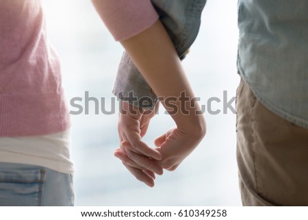 Young happy couple holding hands, touching fingers. Husband and wife supporting each other, teenagers dating, family sharing future, together concept. Close up, cropped image  Royalty-Free Stock Photo #610349258