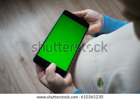 A child is holding a smart phone close-up of a phone with a green screen for keying. Concepts of using gadgets by children