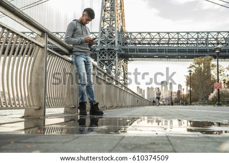 A young man sits and admires the view of NYC's Williamsburg Bridge. Shot during the Autumn of 2016 in Brooklyn, New York City.