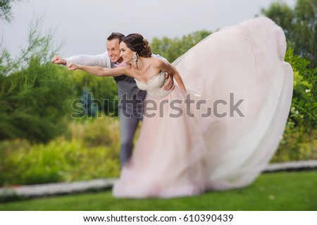 Newlyweds in a superman pose on a green lawn background, park.