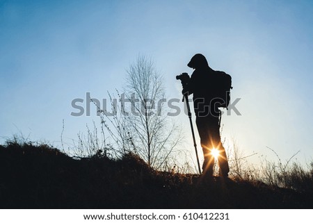 silhouette of young men takes video with camera on tripod ?n the Sunset