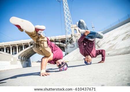 Two bbys ding some stunts - Street artist breakdancing outdrs Royalty-Free Stock Photo #610437671