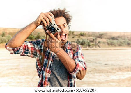 Cheerful african young man taking pictures and having fun on the beach