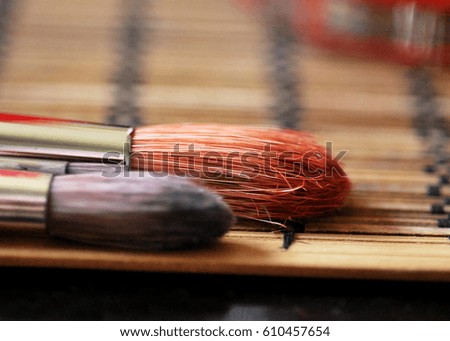 A closeup picture of two brushes colored salmon and purple lying on a mat on a table