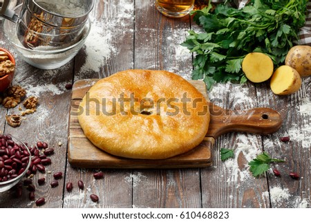 Georgian khachapuri with cheese and spinach / potatoes / beans / meat on a wooden background. Georgian snack. Georgian cuisine.
