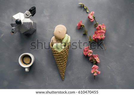 Coffee and macarons in ice cream cone on cement background 