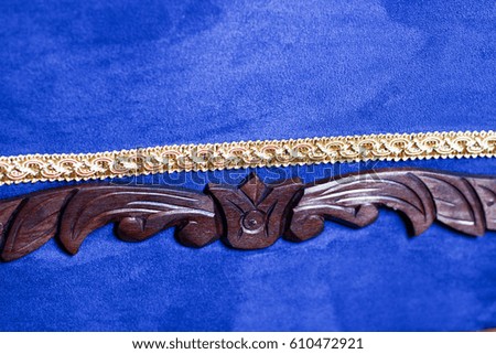 Detail of art wooden carving design element of leaves and wings on blue sofa