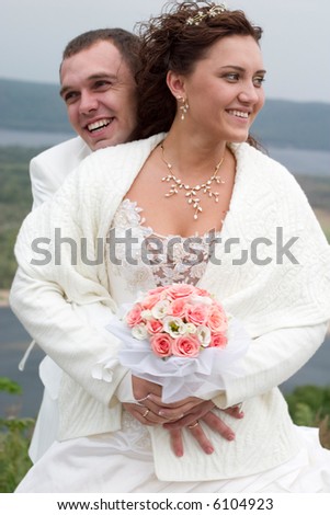 just married - young couple in wedding wear with bouquet of roses. Focus is on bride's face