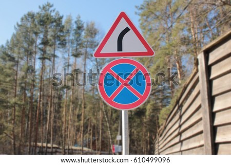 Traffic signs give way and you can't stop in a forest and fences