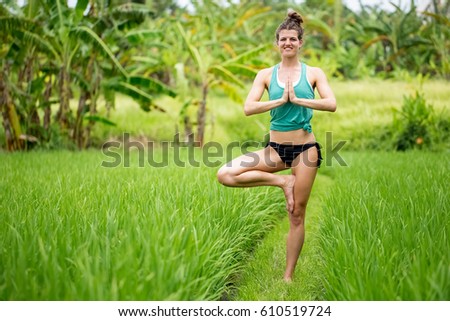 Happy Woman Standing in Tree Yoga Pose on Grass
