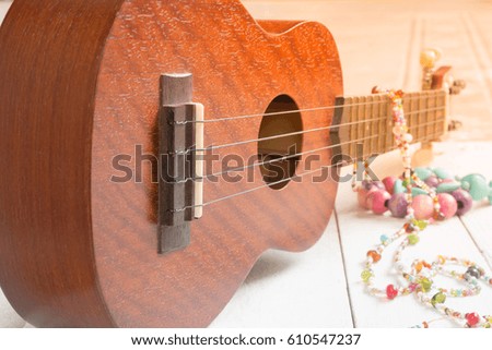 Ukulele, Hawaiian guitar, necklace and bracelet on white wood background 