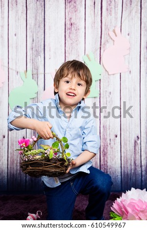 Smiling little toddler boy holding a basket of colorful Easter eggs. Spring and Easter art and crafts for children. Easter egg hunt