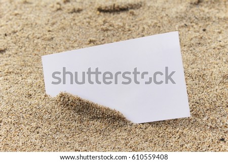 Blank white business card in sand.