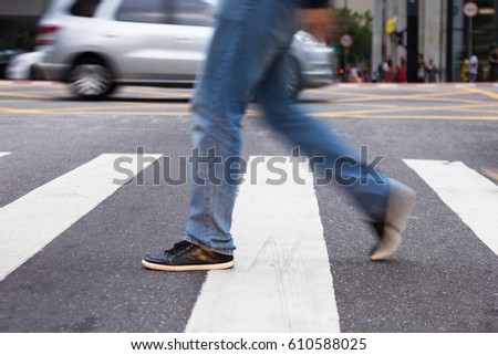 Man crossing pedestrian lane. Blurred by movement. Royalty-Free Stock Photo #610588025