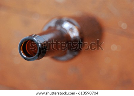 A closeup picture of a dark beer bottle neck