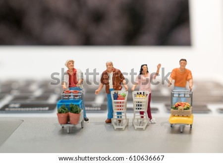 Shopping and e-commerce concept. Miniature people : Group of miniatures with shopping cart toy figure on laptop computer