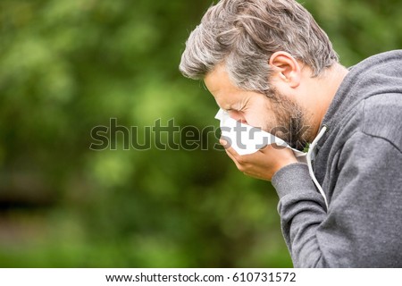 Man with allergy or an infection sneezing  Royalty-Free Stock Photo #610731572