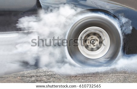 Drag racing car burns rubber off its tires in preparation for the race Royalty-Free Stock Photo #610732565