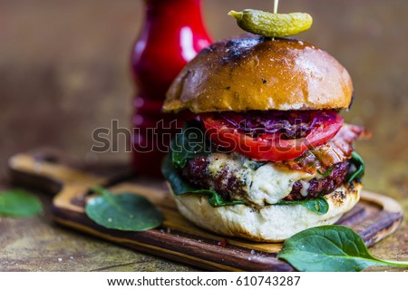 Tasty burger with beef with spinach and blue cheese served on a small board on a vintage background.