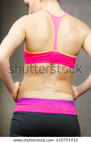 Woman with kinesiotaping application for back pain. Backache alternative kinesio tape therapy method. Health and body care.