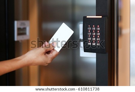 Door access control - young woman holding a key card to lock and unlock door. Royalty-Free Stock Photo #610811738