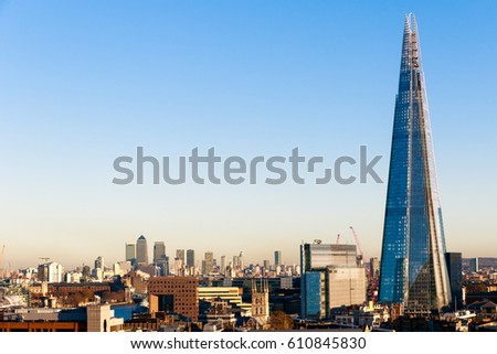 Financial district cityscape of London, including Canary Wharf and The Shard against a blue cloudless sky Royalty-Free Stock Photo #610845830