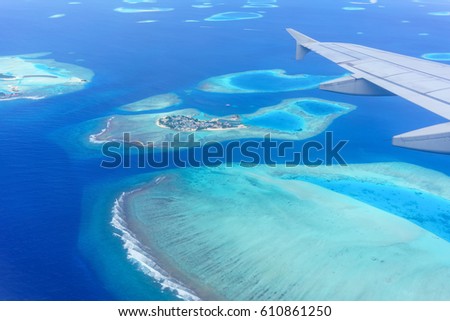 Scenery from airplane 's window seeing wing of airplane , white clouds , blue sky and Maldives islands  Royalty-Free Stock Photo #610861250