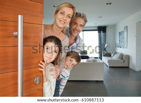 Family of four opening house front door Royalty-Free Stock Photo #610887113