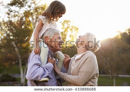 Grandparents Giving Granddaughter A Shoulder Ride In Park Royalty-Free Stock Photo #610888688