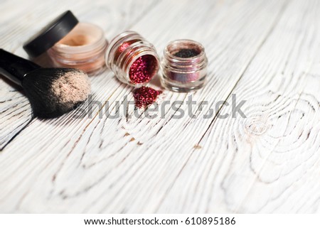 collection of cosmetics for make-up artist. Powder, pigments, glitter, brushes and eyeliner. studio photo on a wooden background