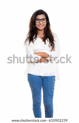 Studio shot of young happy Persian woman smiling and wearing eyeglasses with arms crossed isolated against white background