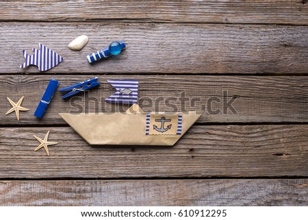 Paper ship and fish on wooden background. Studio photo.