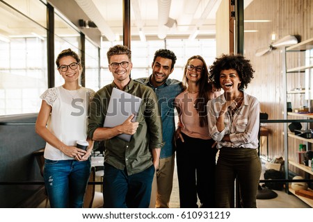 Portrait of creative business team standing together and laughing. Multiracial business people together at startup. Royalty-Free Stock Photo #610931219